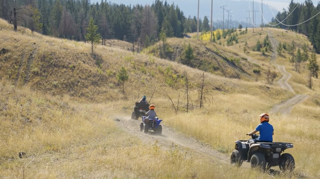 Families riding ATVs on community forest trails near Logan Lake